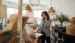 Smiling Asian woman talking on a cellphone in her store
