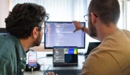 Programmers engrossed in deep collaboration, diligently working together to solve complex problems and develop innovative mobile applications with seamless functionality.