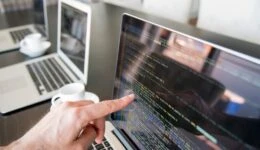 Hand pointing to line of code on computer screen.